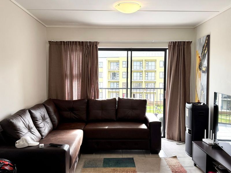 A living room featuring tiled flooring and a sliding glass door that provides access to a balcony.