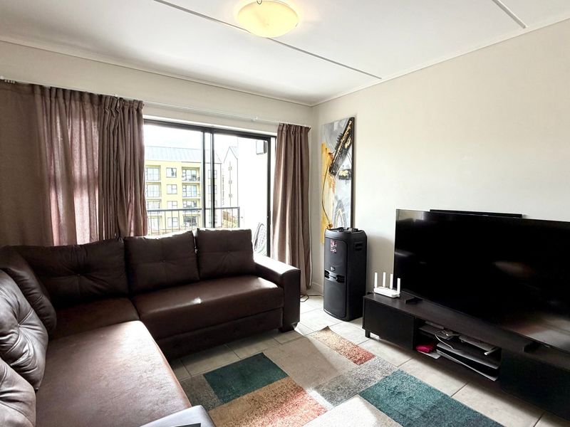 A living room featuring tiled flooring and a sliding glass door providing access to an outdoor balcony area.