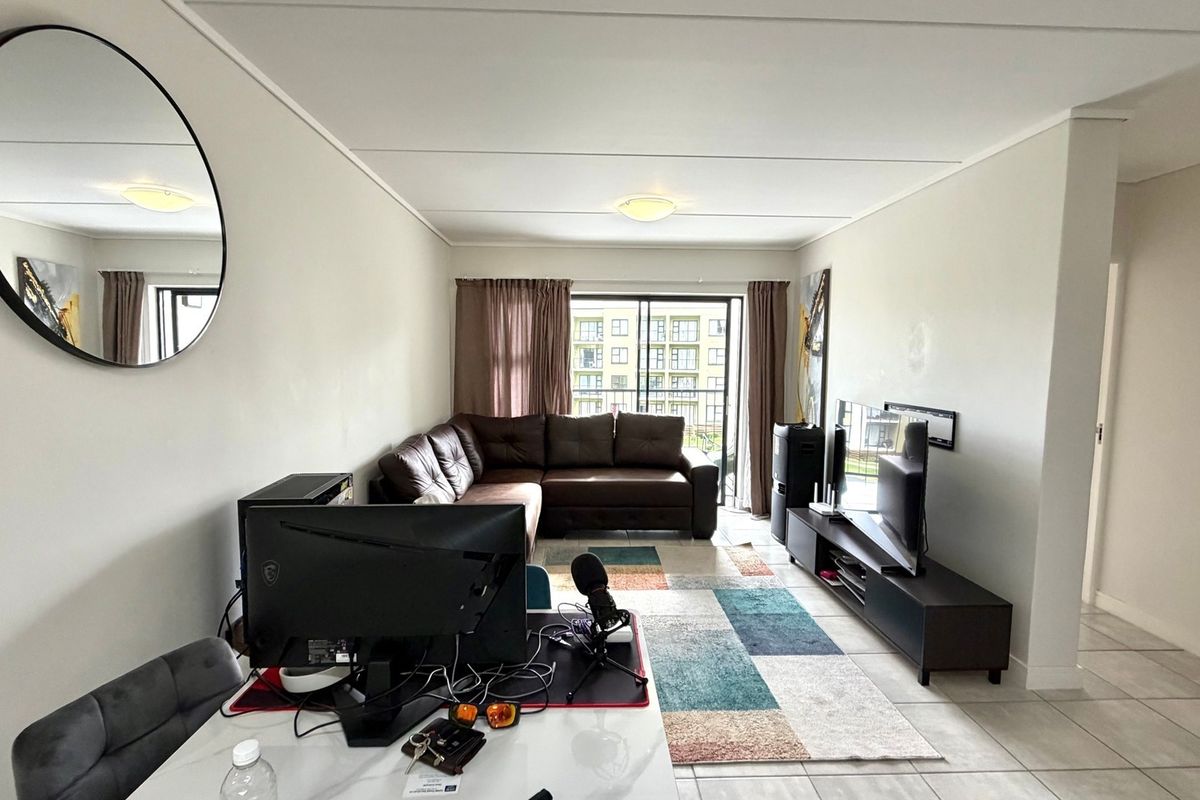 A living room featuring tiled flooring and a sliding glass door leading to a balcony, providing natural light to the space.