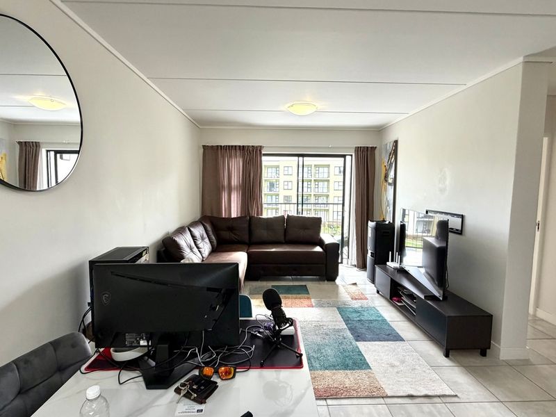 A living room featuring tiled flooring and a sliding glass door leading to a balcony, providing natural light to the space.