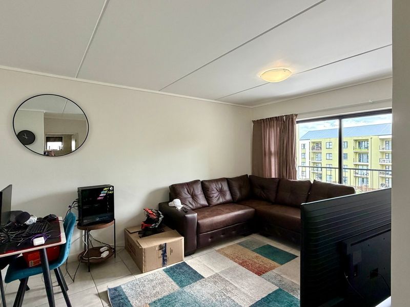 A living room featuring tiled flooring and a large sliding glass door that provides natural light and access to a balcony.