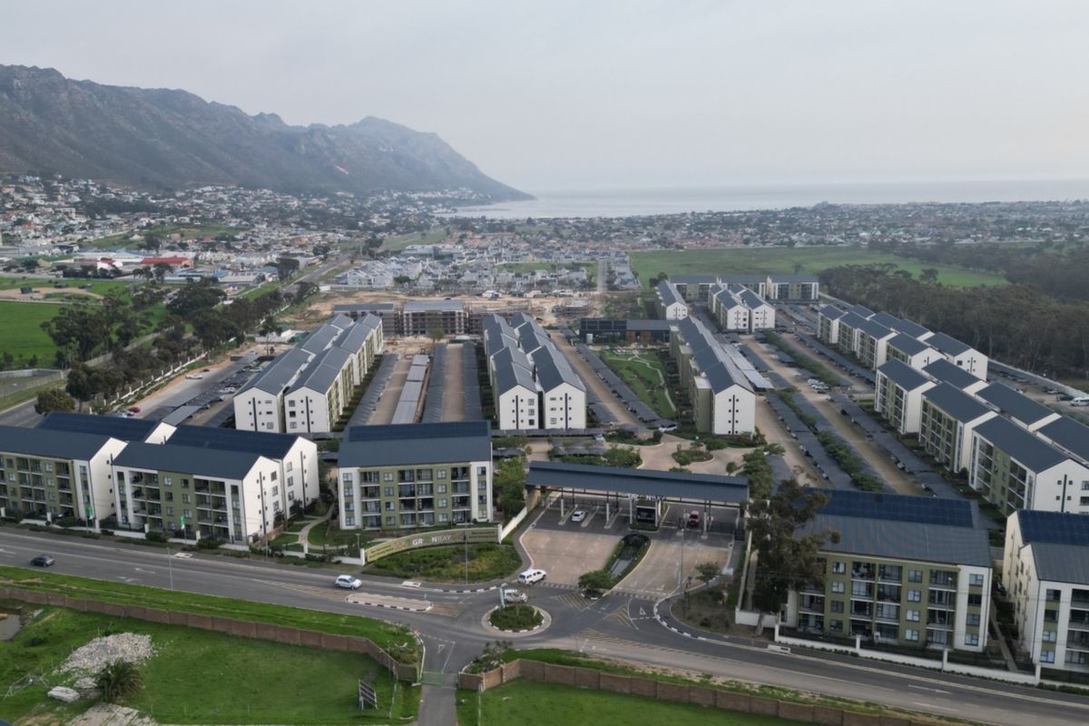 Aerial view of a modern apartment complex featuring multiple residential blocks, secure gated access, parking facilities, and solar energy infrastructure.