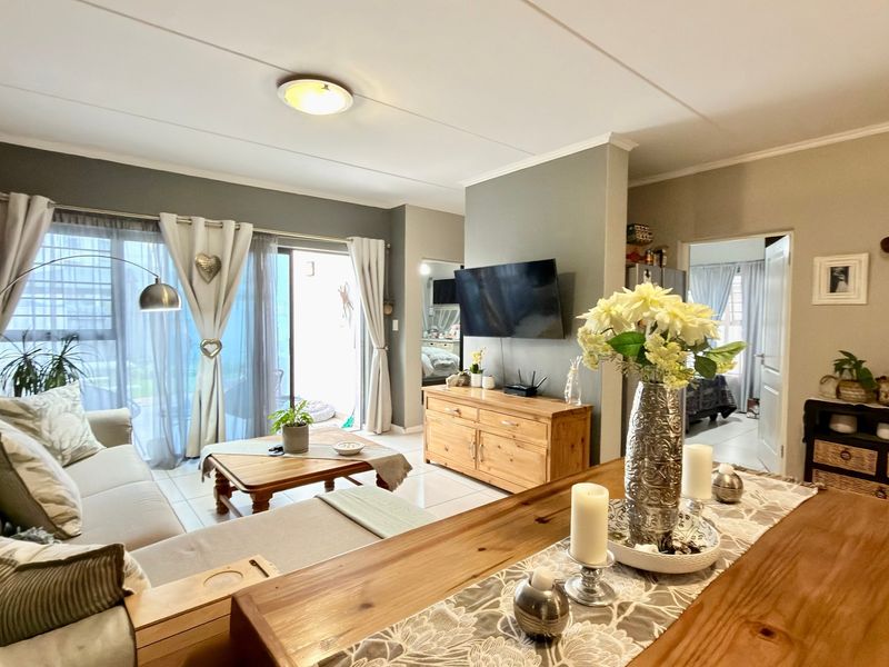 An open-plan living and dining area featuring tiled floors, a partition wall, and a sliding glass door leading to an outdoor space.