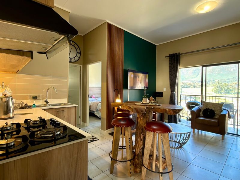 Open-plan living area featuring a modern kitchen with gas hob, tiled flooring, and sliding doors leading to a balcony with scenic views.