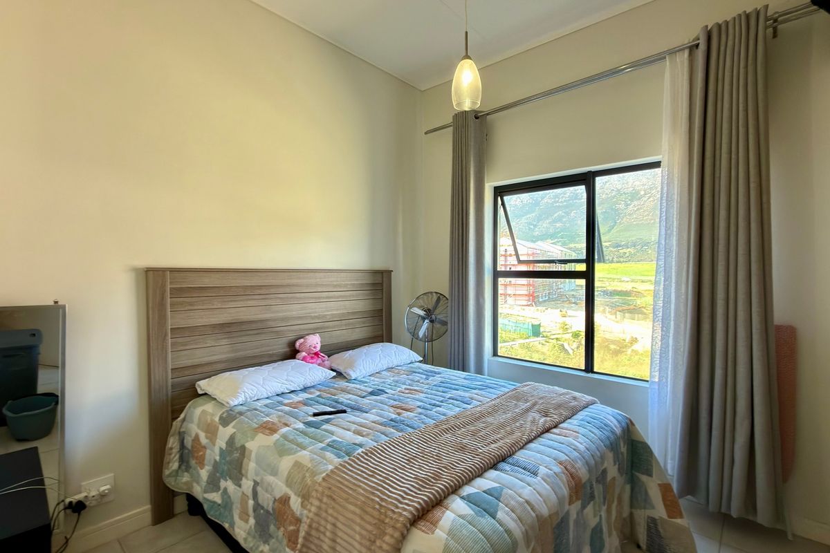 A well-lit bedroom featuring a built-in wardrobe, neutral wall finishes, and a window with views of the surrounding area.