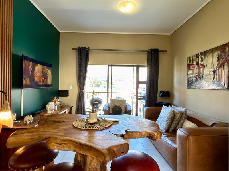Open plan living area featuring tiled flooring, a feature wall with slatted wood paneling, and a sliding glass door leading to an outdoor space.