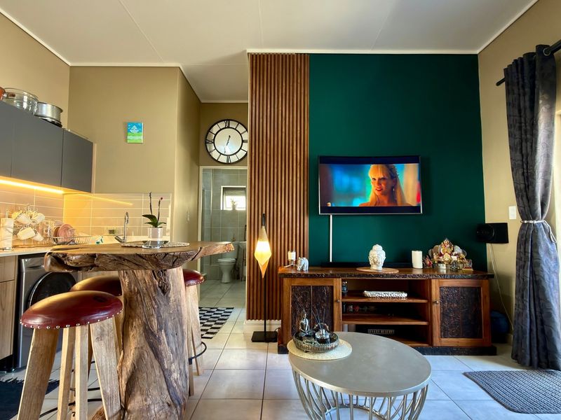 Modern open-plan living area featuring a contemporary kitchen with sleek cabinetry, a striking slatted wood feature wall, and direct access to the living space.