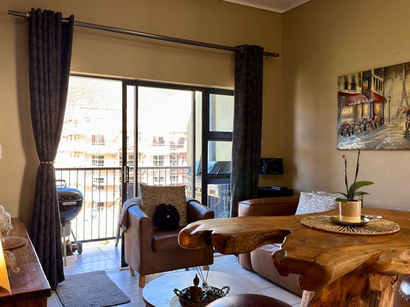 A comfortable living area featuring a large sliding glass door that opens onto a private balcony with metal railings.