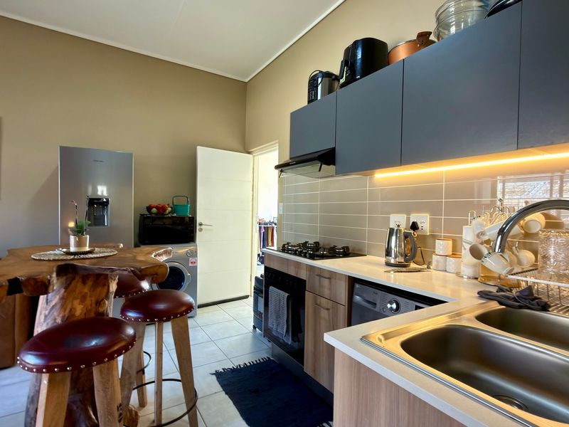 Modern open-plan kitchen featuring sleek cabinetry, gas hob, integrated appliances, and under-cabinet lighting, seamlessly flowing into the living area.