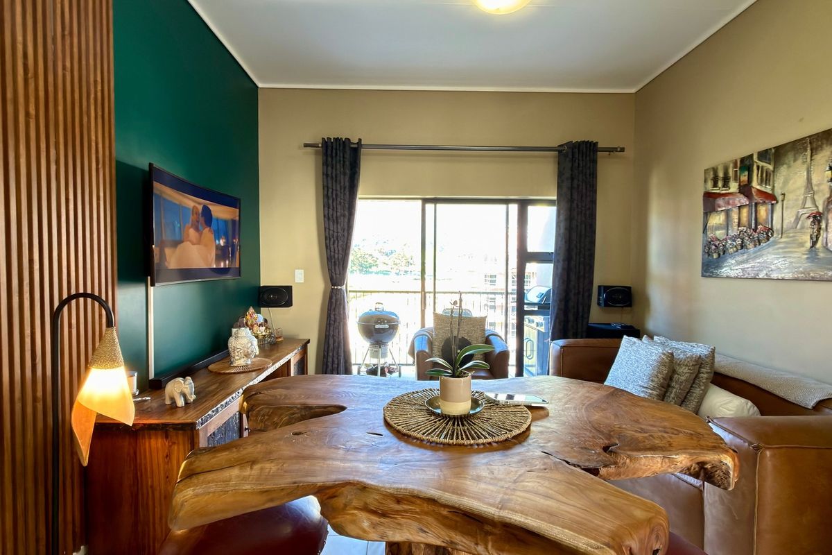 A well-maintained living room featuring a distinctive timber slat feature wall, neutral paint tones, and a large sliding door providing access to the balcony.