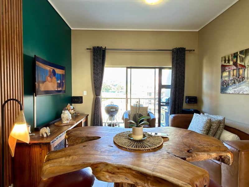 A well-maintained living room featuring a distinctive timber slat feature wall, neutral paint tones, and a large sliding door providing access to the balcony.