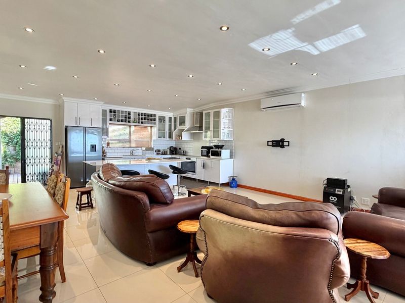 Spacious open-plan living area featuring a modern kitchen with island, tiled floors, recessed lighting, and direct access to the outdoor area.