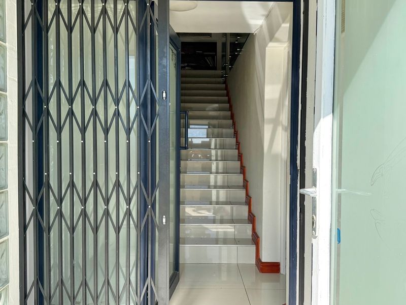 Entrance area featuring a security gate, glass block wall, and a tiled staircase leading to the upper level.