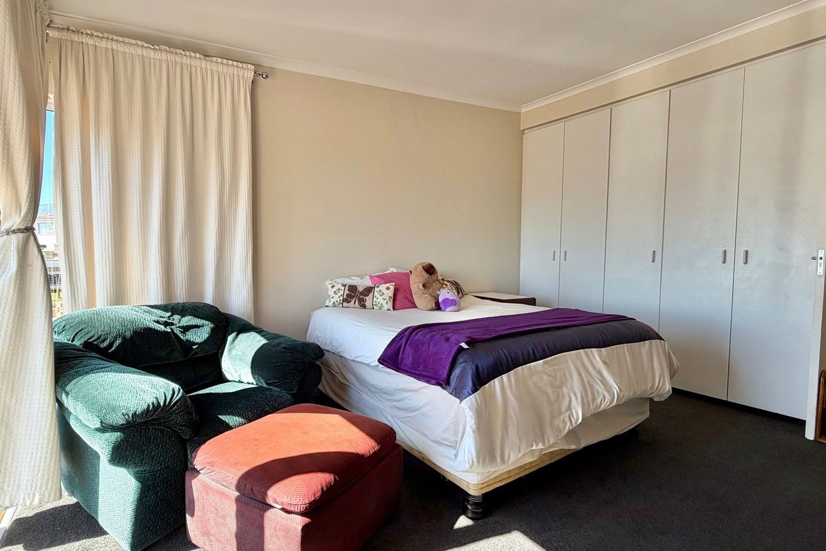 A bedroom featuring built-in cupboards, carpeted flooring, and a sliding glass door providing natural light.