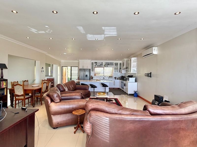 Spacious open-plan living area featuring a modern kitchen with island, tiled floors, recessed lighting, and a split-system air conditioner.