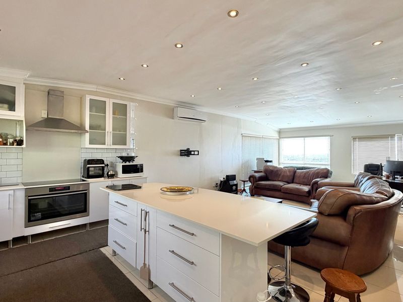 Spacious open-plan kitchen and living area featuring a central island, modern cabinetry, built-in appliances, and recessed lighting throughout.