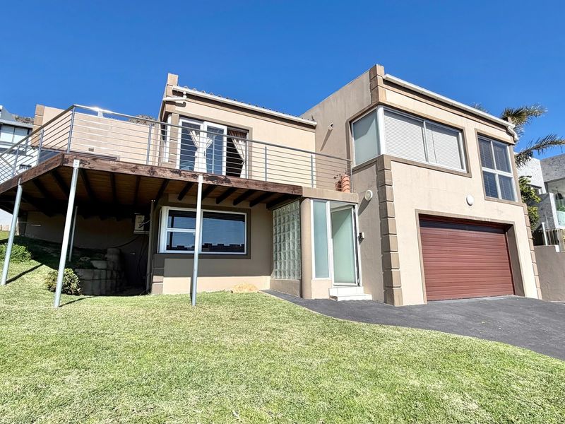 Front elevation of a multi-level house featuring a raised wooden deck with stainless steel balustrades, a single garage, and a landscaped lawn area.