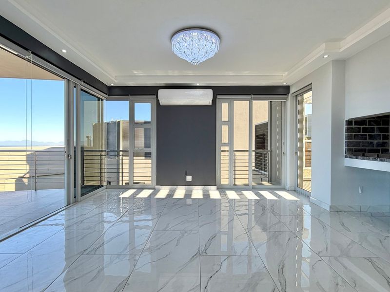 Spacious, modern living area featuring polished marble-look floor tiles, a built-in fireplace, split-system air conditioning, and expansive sliding doors leading to a balcony.