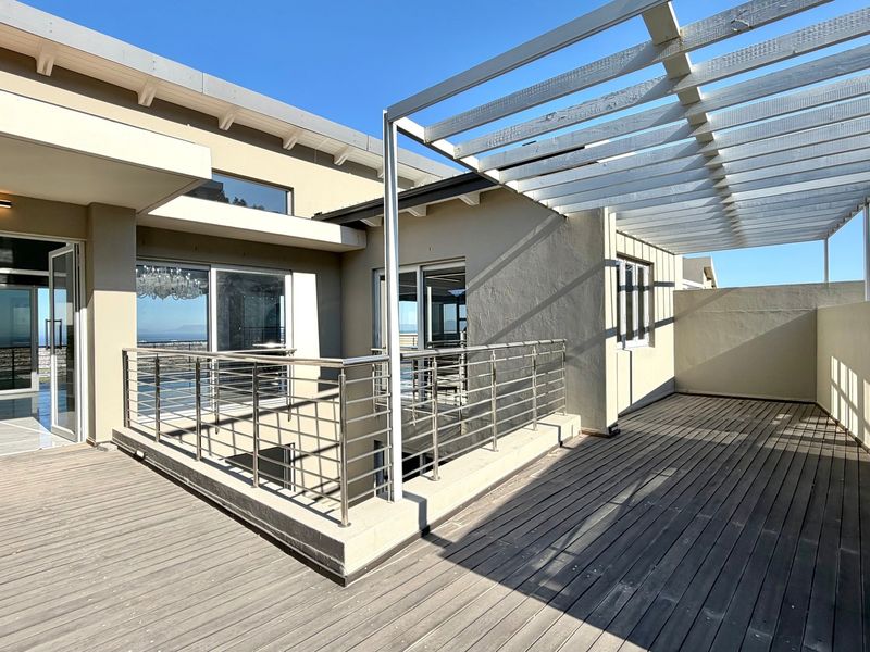 Spacious outdoor balcony featuring timber decking, a modern pergola, and stainless steel balustrades, offering a seamless transition from the interior living spaces.