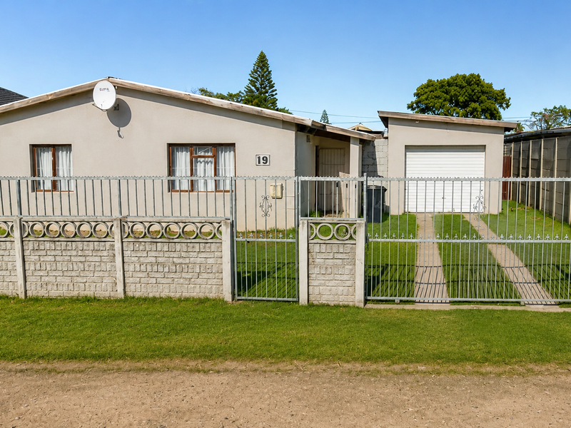 Front elevation of a single-story house featuring a metal perimeter fence, concrete boundary wall, and an attached single garage with a driveway.