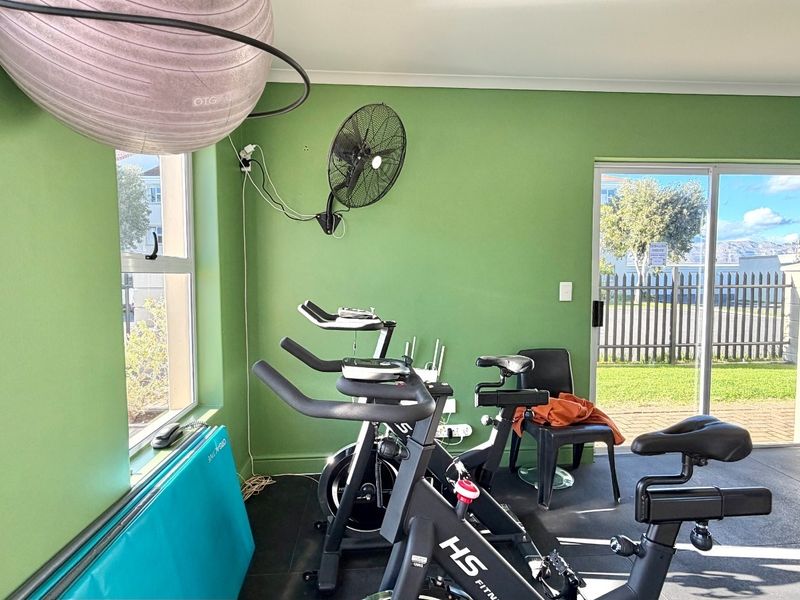 A functional apartment gym space featuring rubberized flooring, a large wall mirror, and sliding glass door access to the exterior.