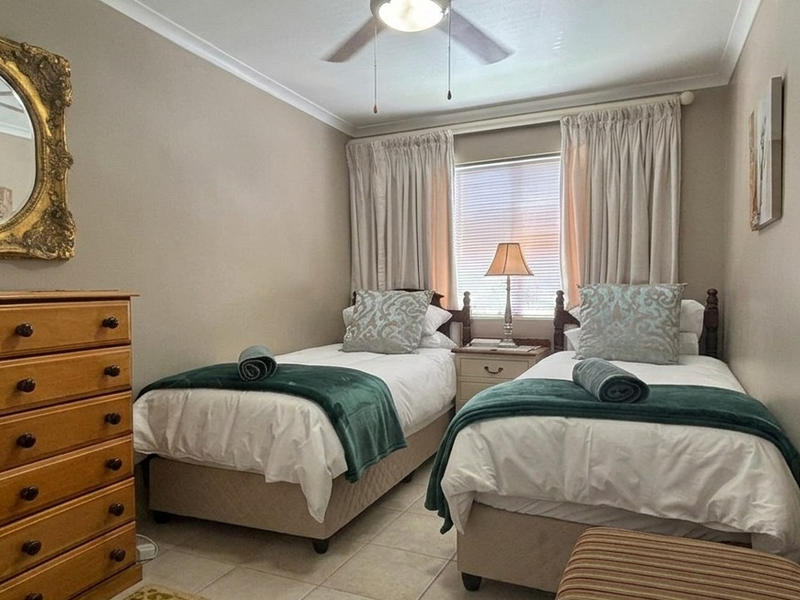 A compact bedroom featuring tiled flooring, a ceiling fan, and neutral wall finishes, suitable for a guest room or children's bedroom.