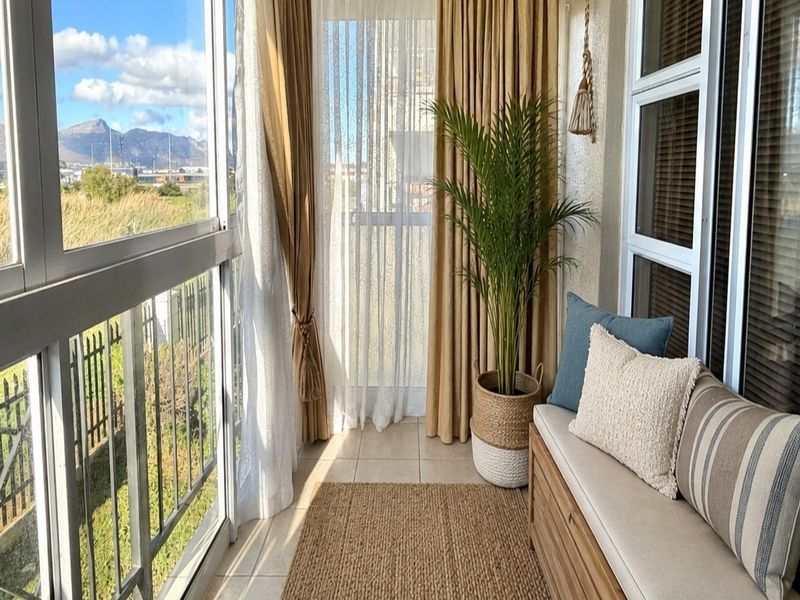 Enclosed balcony featuring tiled flooring, large aluminum sliding windows, and views of the surrounding landscape.