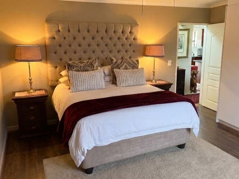 A well-maintained bedroom featuring laminate flooring, neutral wall tones, and ample built-in cupboard storage space.