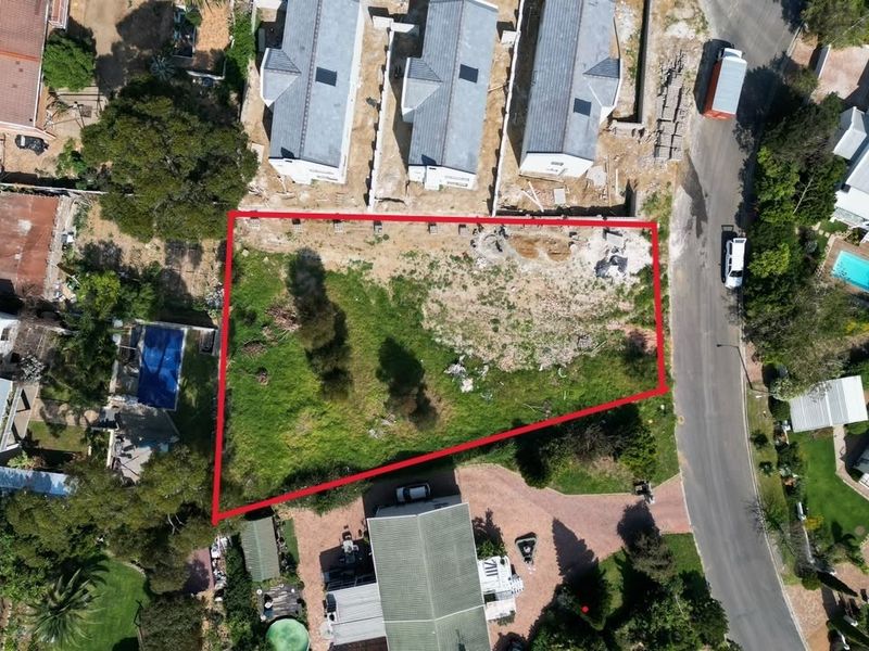 An aerial view of a vacant residential plot outlined in red, situated within an established neighborhood with surrounding residential properties.