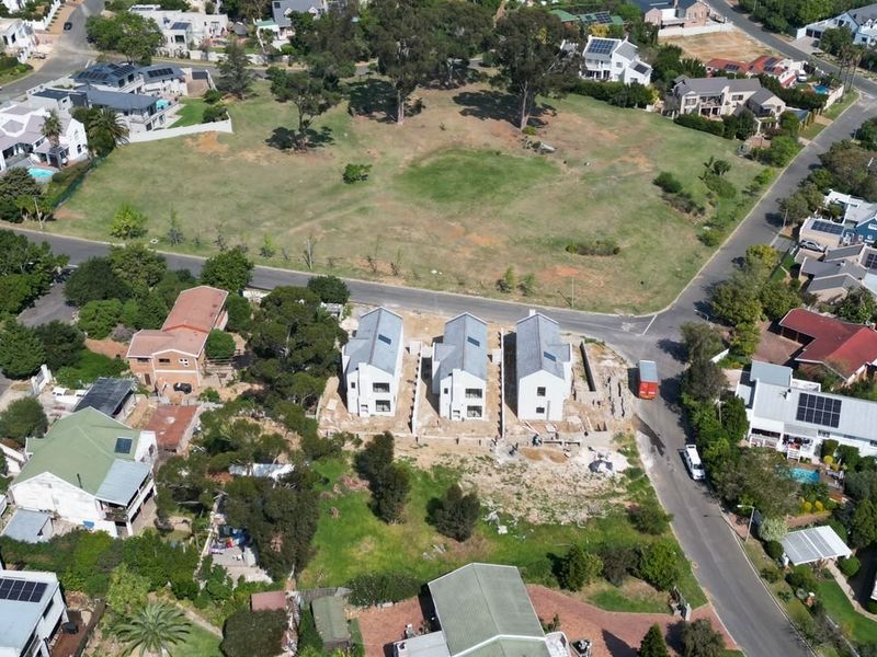 Aerial view of a residential development site featuring three newly constructed homes situated within an established suburban neighborhood.