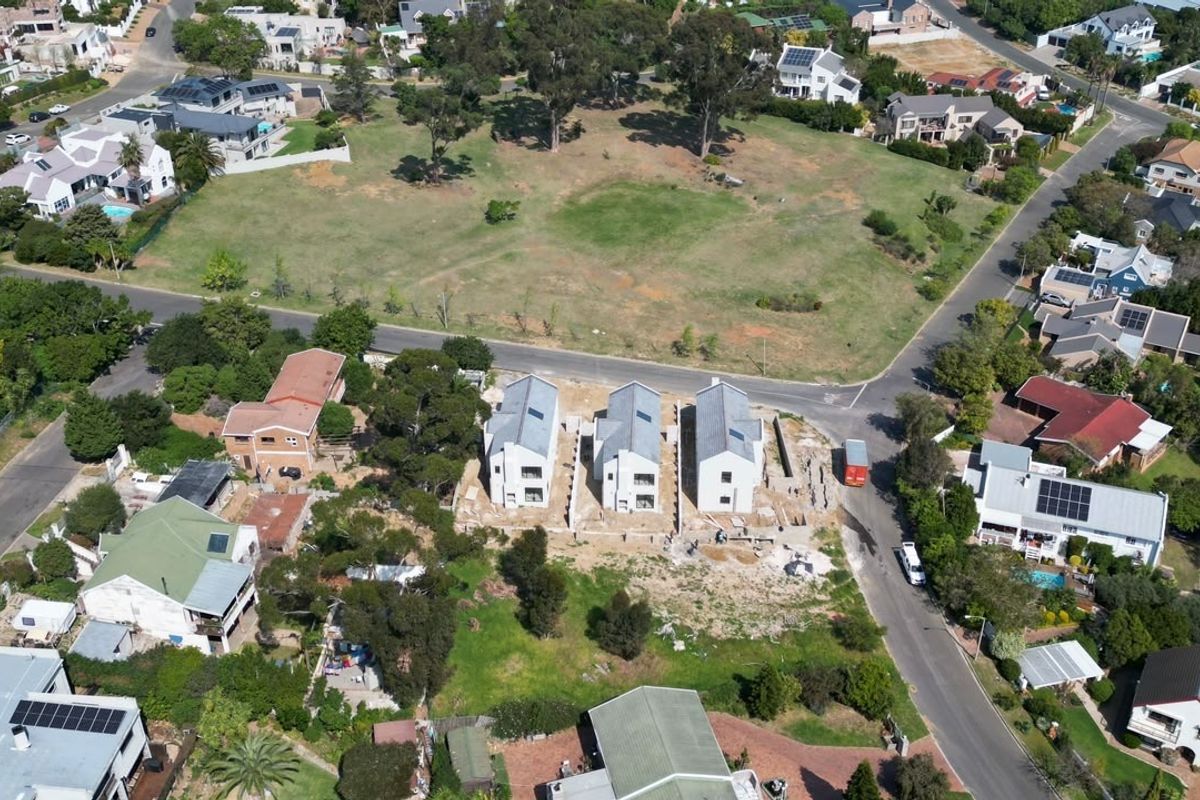 Aerial view of a residential development site featuring three newly constructed homes situated within an established suburban neighborhood.