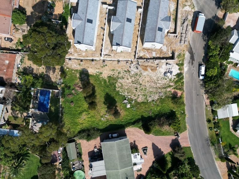 Aerial view of a vacant residential plot situated within an established neighborhood, showing surrounding properties and access road.