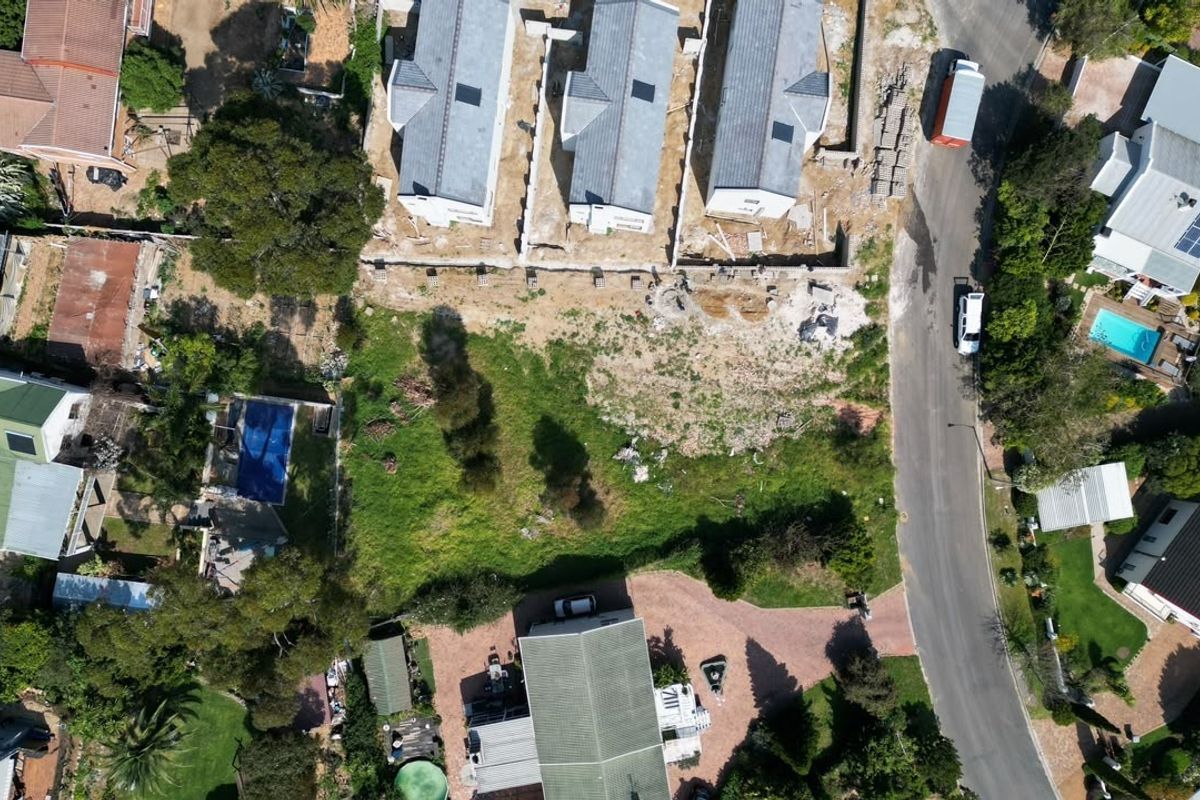 Aerial view of a vacant residential plot situated within an established neighborhood, showing surrounding properties and access road.