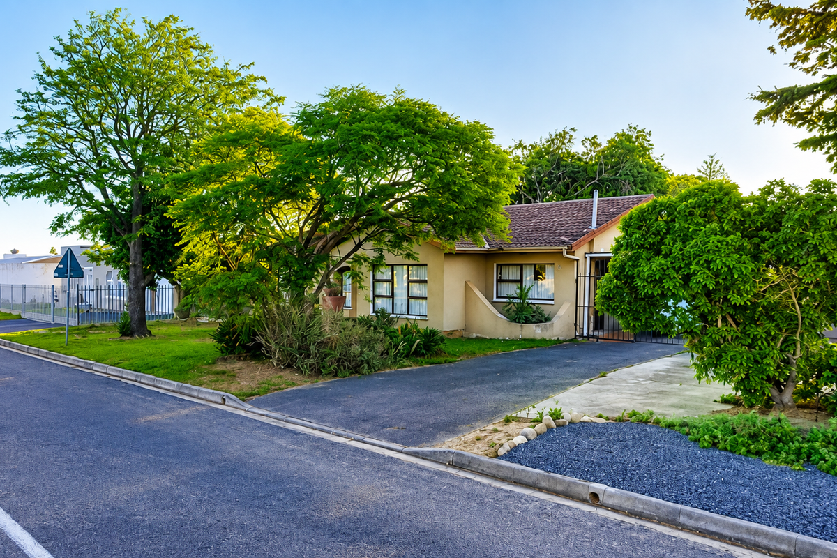 Front view of a single-story residential house featuring a paved driveway, established garden, and tiled roof, situated in a quiet suburban street.