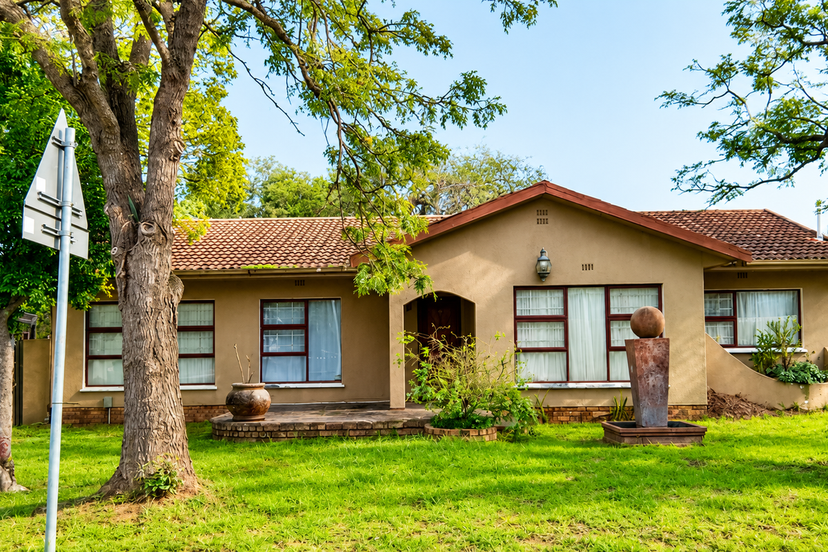 A charming single-story residence featuring a tiled roof, brick facade, and a well-maintained front garden with a decorative water feature.