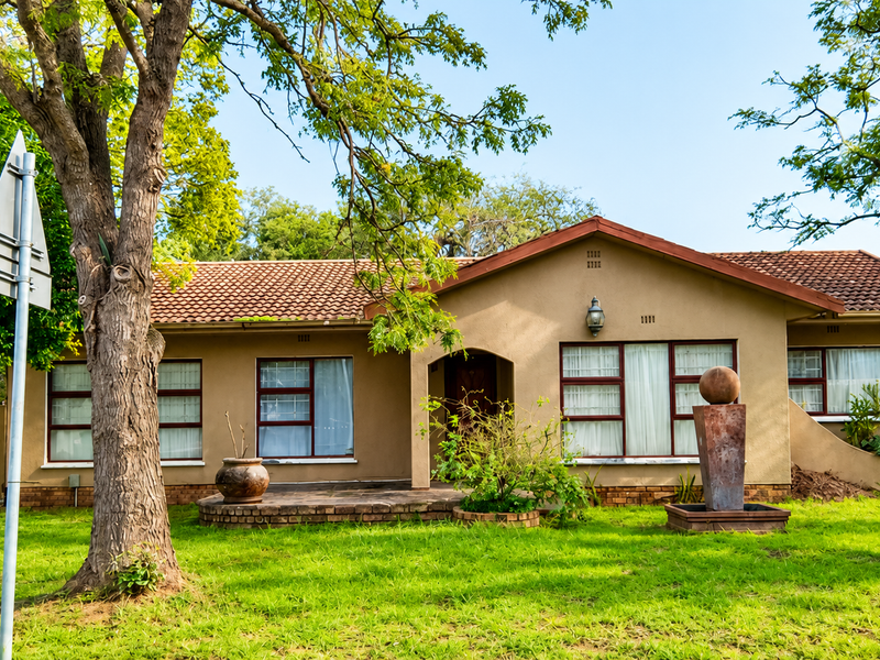 A charming single-story residence featuring a tiled roof, brick facade, and a well-maintained front garden with a decorative water feature.
