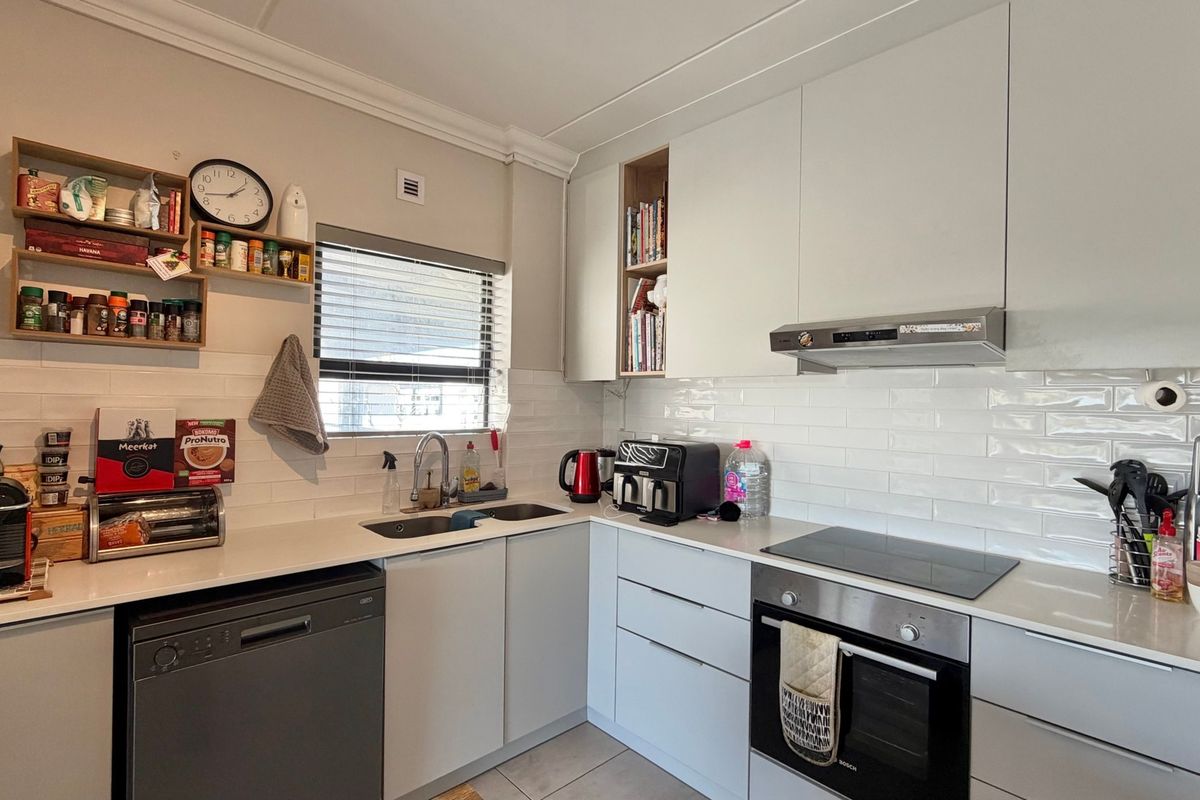 A modern, well-maintained kitchen featuring sleek white cabinetry, subway tile backsplash, integrated appliances, and durable quartz countertops.
