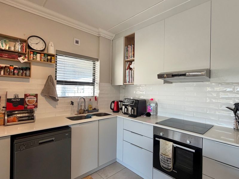 A modern, well-maintained kitchen featuring sleek white cabinetry, subway tile backsplash, integrated appliances, and durable quartz countertops.