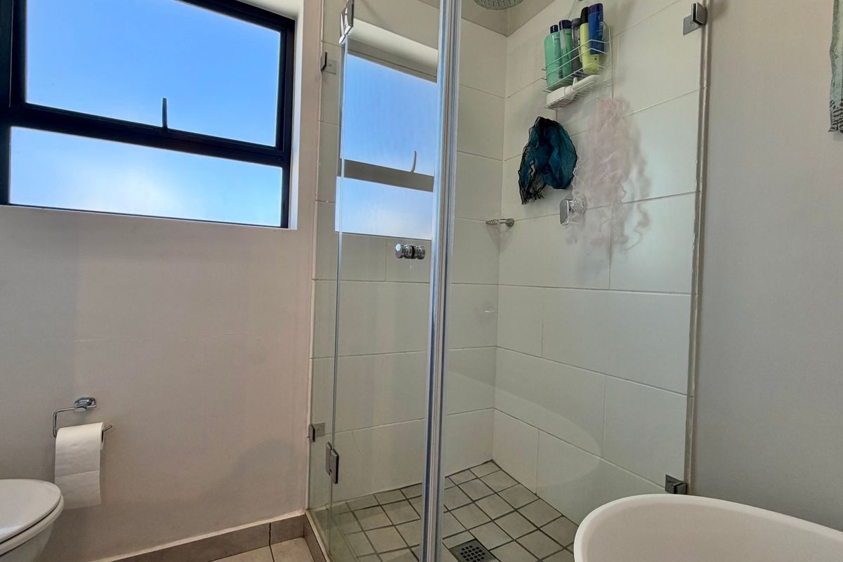 A functional bathroom featuring a glass-enclosed shower, tiled walls, and a standard toilet, providing a clean and practical layout.