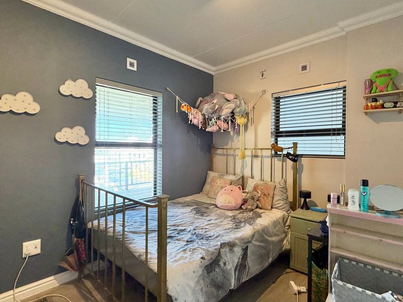 A bedroom featuring dual windows with venetian blinds, decorative cornice, and skirting boards, finished with a feature wall.