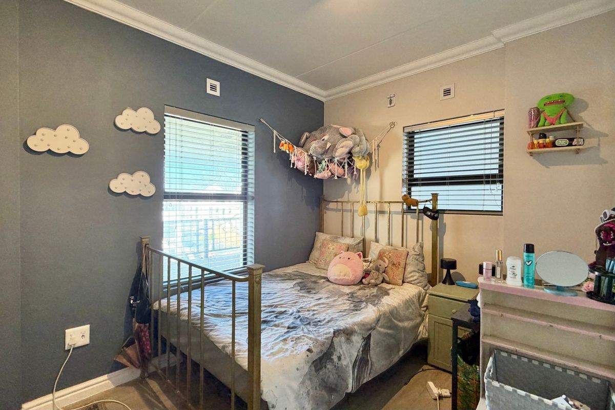 A bedroom featuring dual windows with venetian blinds, decorative cornice, and skirting boards, finished with a feature wall.