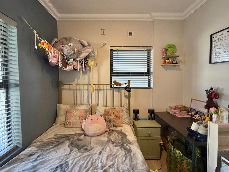 A bedroom featuring dual windows with venetian blinds, decorative cornice detailing, and neutral wall finishes.