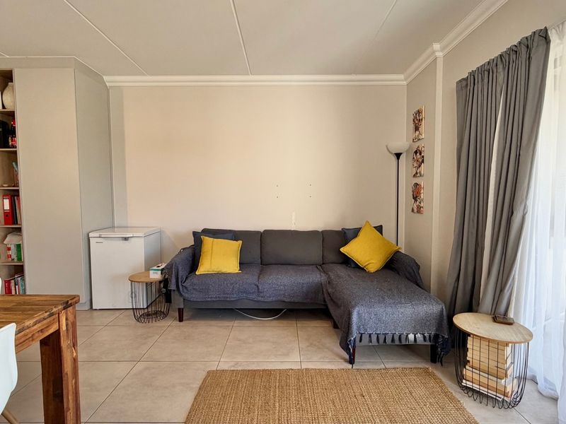 A living room featuring tiled flooring, built-in cabinetry, and a sliding glass door providing access to the outdoor area.