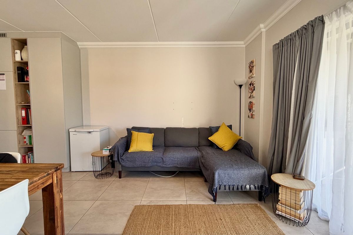 A living room featuring tiled flooring, built-in cabinetry, and a sliding glass door providing access to the outdoor area.
