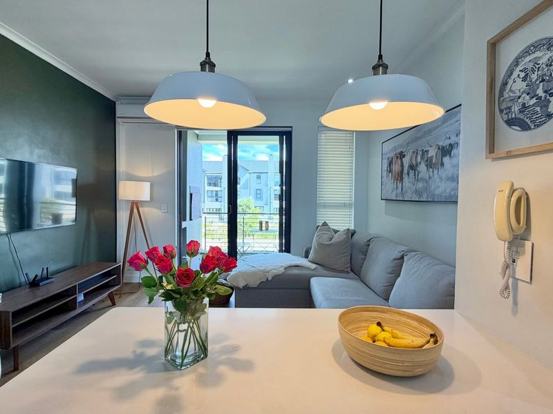 Modern open-plan living area featuring a sleek countertop, contemporary pendant lighting, and a sliding glass door leading to a private balcony.