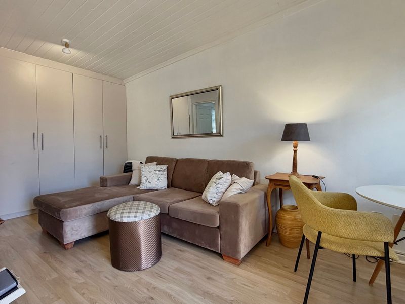 A well-maintained living area featuring light laminate flooring, a timber panelled ceiling, and ample built-in cupboard storage.