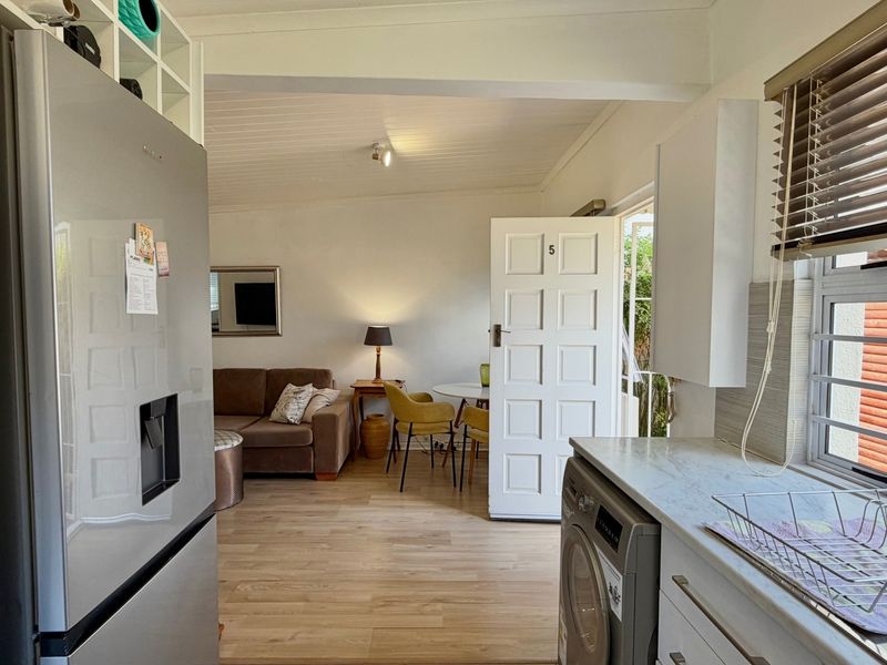 Open plan living area featuring laminate flooring, integrated kitchen cabinetry, and direct access to the exterior through a panel door.