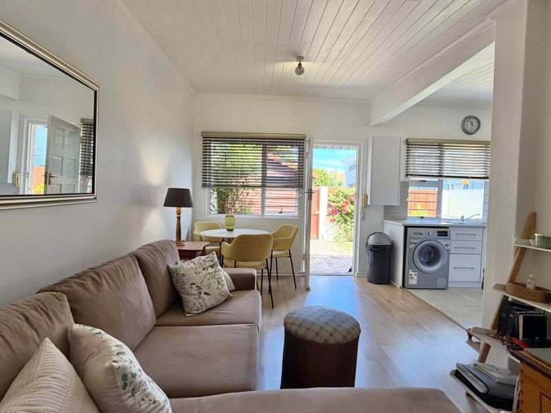 Open-plan living area featuring a kitchen with built-in cabinetry, laminate flooring, and a timber ceiling, with direct access to an outdoor patio area.