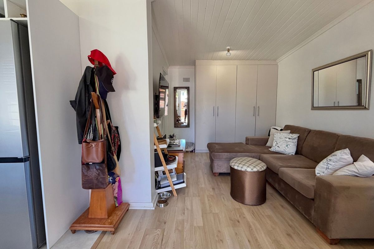 A living room featuring light-toned laminate flooring, a tongue and groove ceiling, and ample built-in storage cupboards.