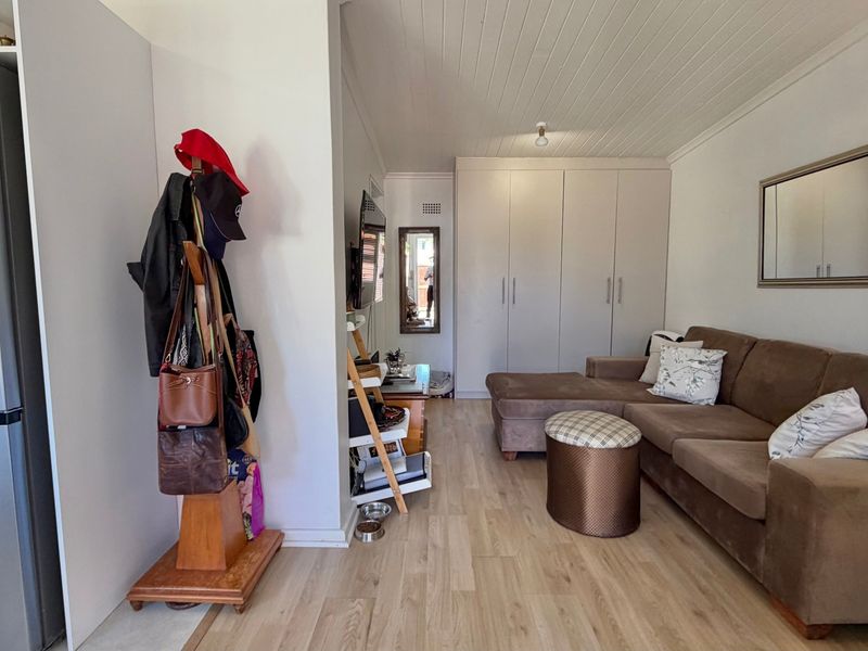 A living room featuring light-toned laminate flooring, a tongue and groove ceiling, and ample built-in storage cupboards.